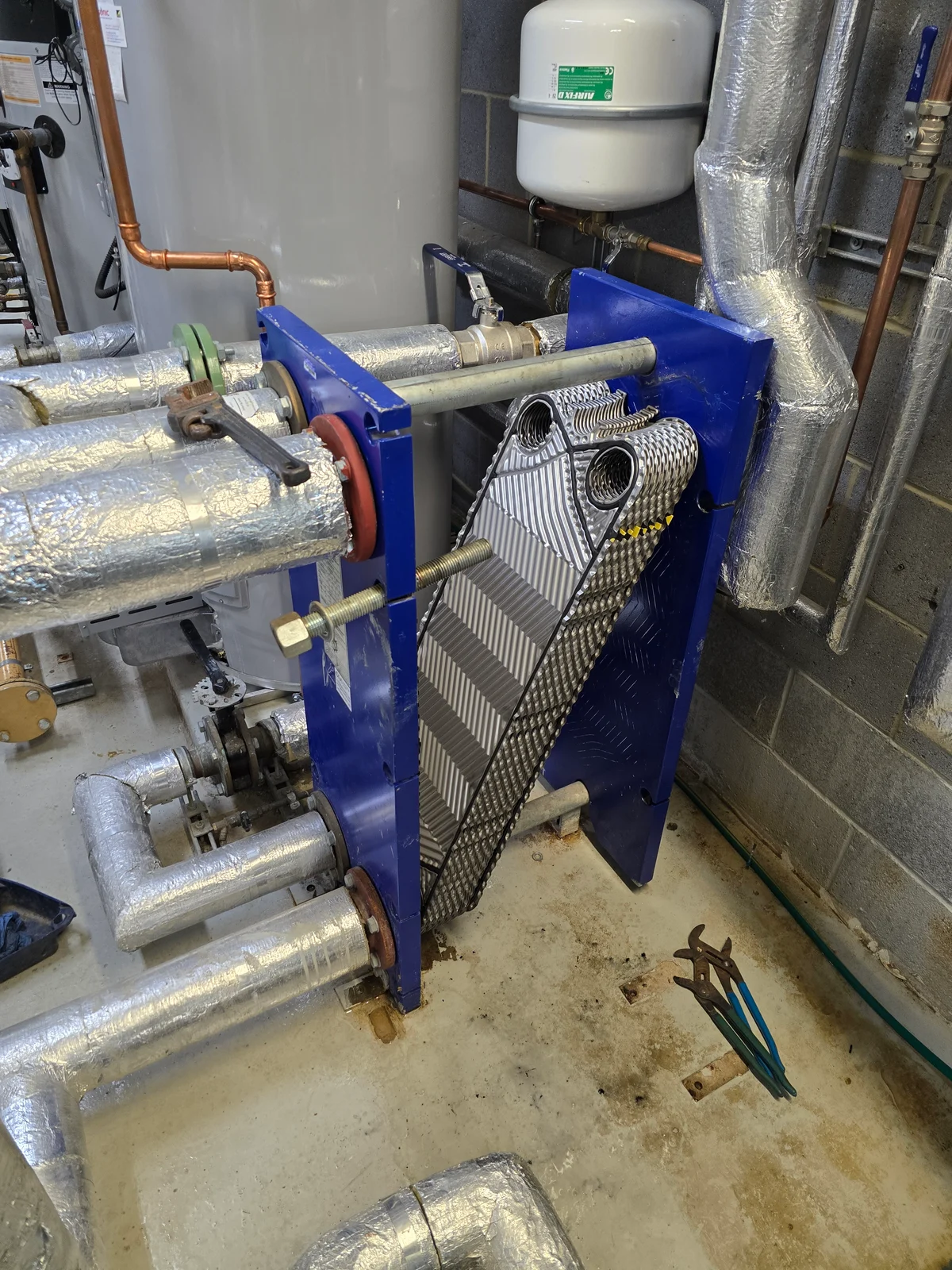 Opened plate heat exchanger with insulated pipework in a commercial plant room
